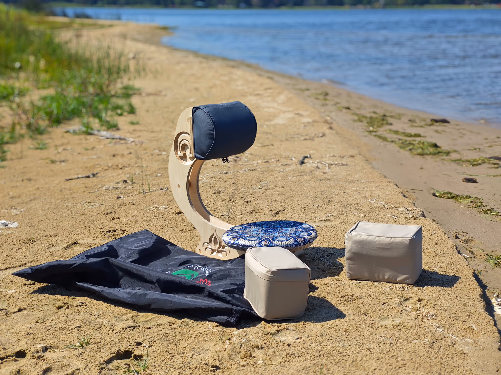 OM Chair set up outdoors near a sandy lakeshore surrounded by trees — portable ergonomic meditation chair by Nature Sense™