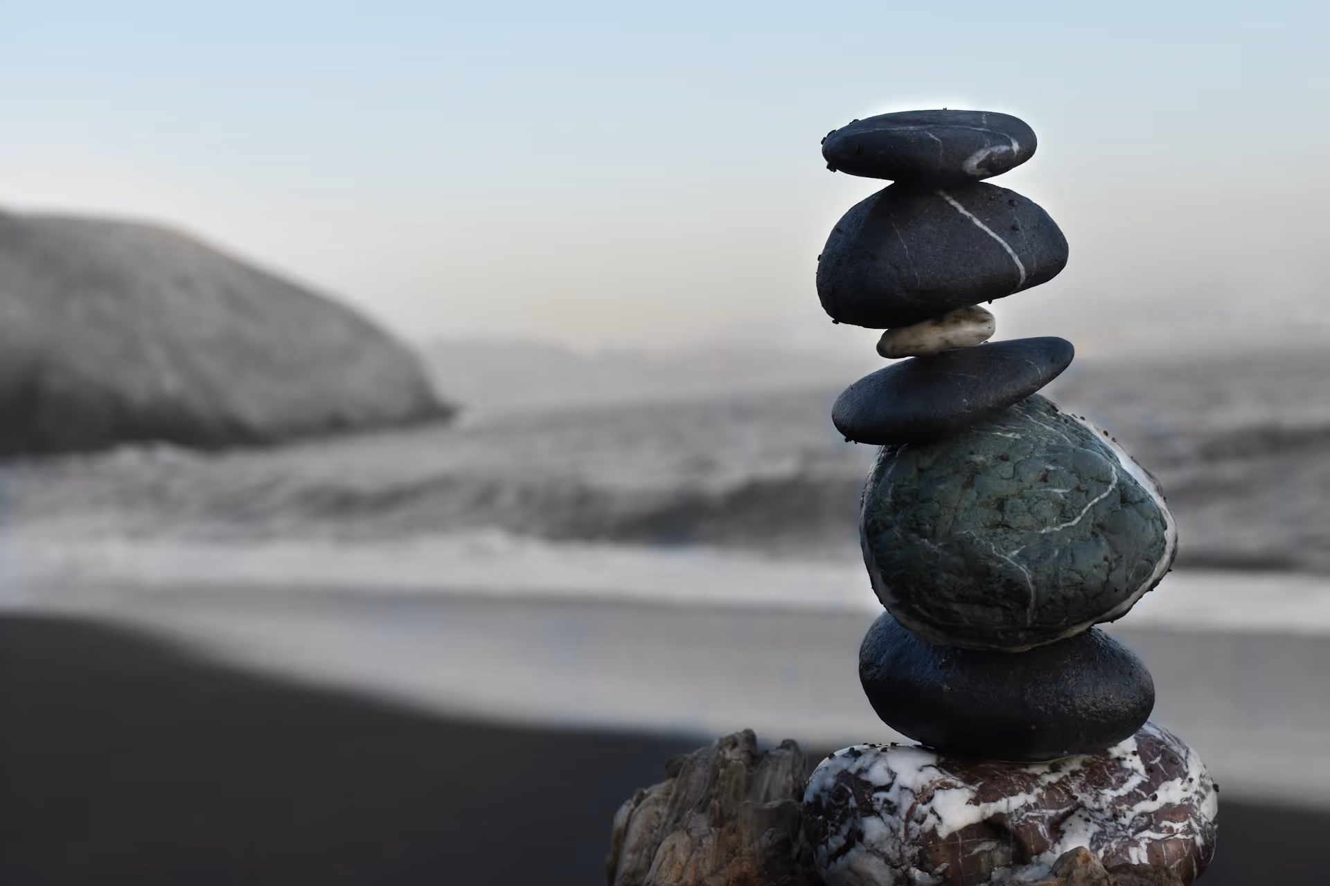 Smooth river stones stacked in a balanced cairn on a rocky beach — symbol of stillness, balance, and connection to nature